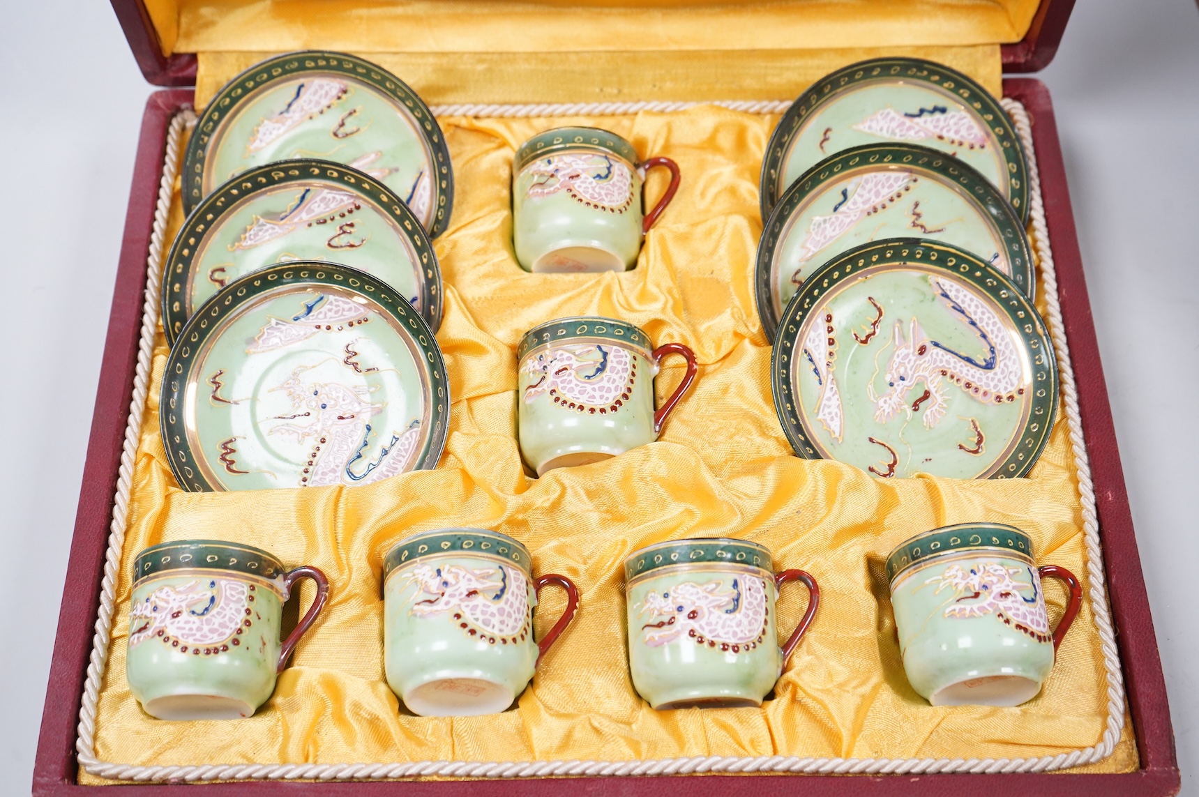 A cased Japanese coffee set, decorated with dragons on a green ground, case 34cm wide